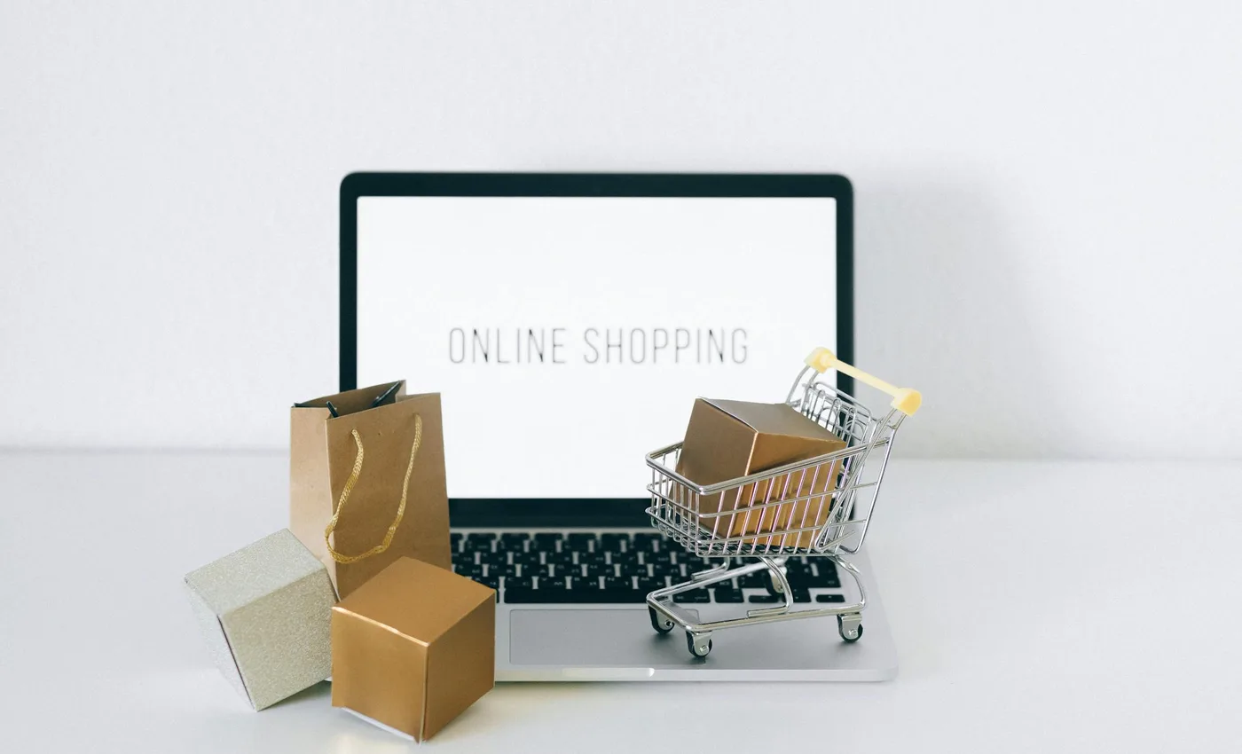 Laptop με online shopping και κουτιά προϊόντων για σύγκριση PrestaShop και WooCommerce